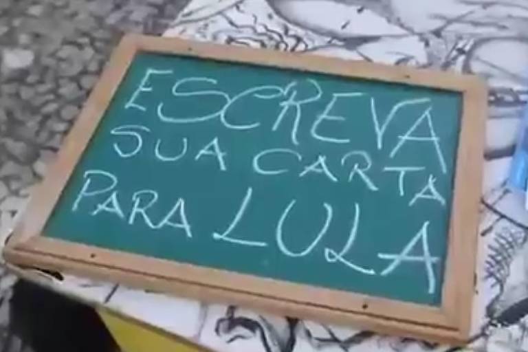O ator Cláudio Ferrário escreve cartas para Lula na prisão para pessoas na rua em uma banca improvisada no centro do Recife
