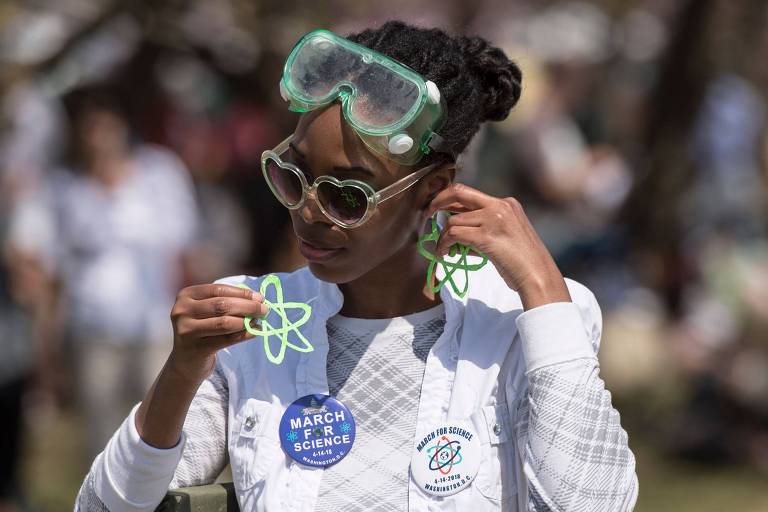 Mulher coloca brincos em formato da estrutura de um átomo para participar da marcha para ciência em Washington, nos EUA