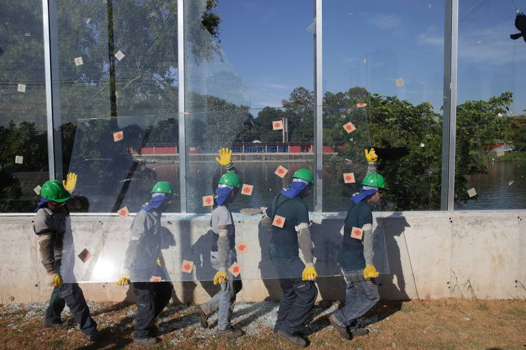 Funcionários carregam novo painel de vidro para substituir o quebrado em 20 de abril, na raia da USP