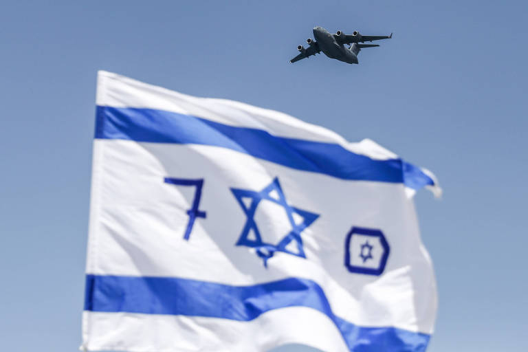Um jato da Força Aérea Israelense sobrevoa um evento em que bandeiras lembram os 70 anos de fundação de Israel