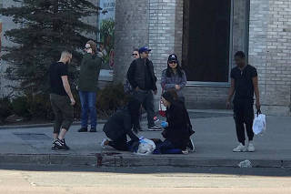 A victim is helped by pedestrians after a van hit multiple people at a major intersection in Toronto