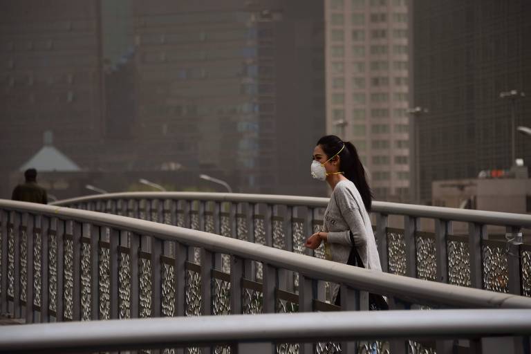 Mulher veste máscara para se proteger da poluição em Pequim, na China