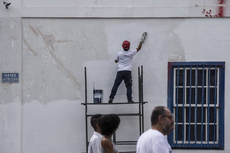 Homem sobre estrutura repara fachada do Pateo do Collegio após pichação