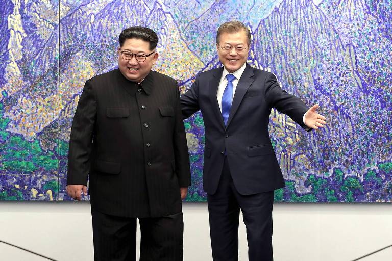 Kim Jong-un aparece de calça e blazer pretos completamente fechado, enquanto Moon Jae-in veste terno preto com camisa branca e gravata azul royal; o sul-coreano coloca a mão esquerda nas costas do colega, enquanto abre a outra mão; ao fundo, uma obra de arte replicando montanhas em que o azul predomina