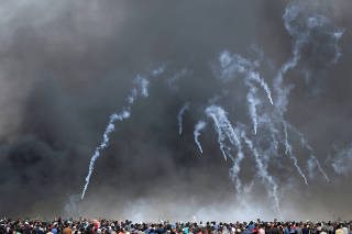 Tear gas canisters are fired by Israeli troops at Palestinian demonstrators during clashes at a protest demanding the right to return to their homeland, at the Israel-Gaza border in the southern Gaza Strip