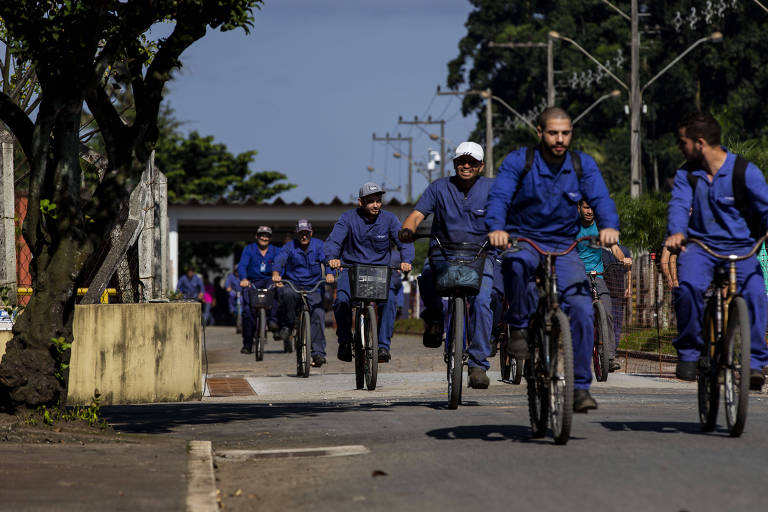 Funcionários da Fundição Tupy, em Joinville (SC), em bicicletas e vestindo os uniformes azuis da empresa