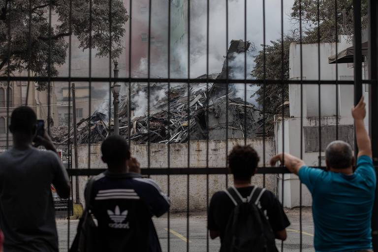 Moradores acompanham trabalho de resgate dos bombeiros após incêndio de grandes proporções provocar o desabamento de prédio, na região central de São Paulo