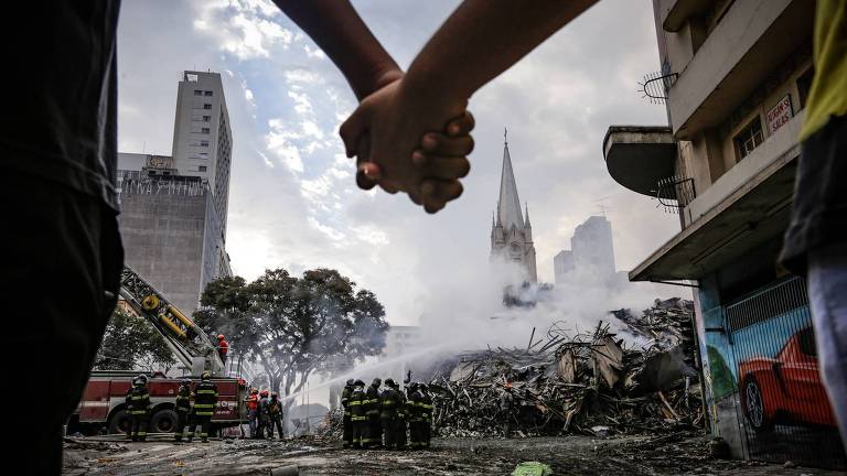 Voluntários fazem cordão de isolamento no entorno do loca do acidente no Largo do Paissandu, região central de São Paulo, na madrugada desta terça-feira (1º)