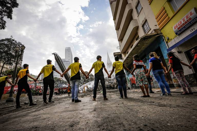 Voluntários fazem cordão de isolamento no entorno do loca do aciedente no Largo do Paissandu, região central de São Paulo, na madrugada desta terça-feira (1º)