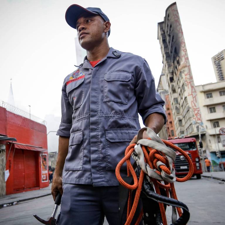 Sargento Diego, o bombeiro que tentou salvar um morador do prédio no exato momento do desabamento, entre os escombros; incêndio de grandes proporções atingiu dois edifícios no centro de São Paulo, um dos prédios desabou