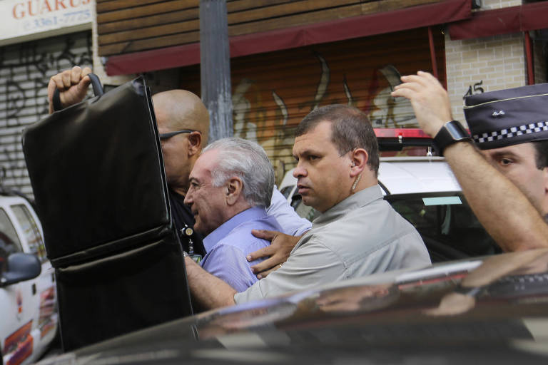 Guarda costas tentam proteger Michel Temer enquanto pessoas gritam e jogam objetos contra ele; o presidente foi à área onde o prédio desabou, no centro de São Paulo