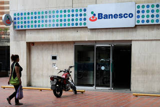 A woman walks in front of a Banesco bank branch in Caracas