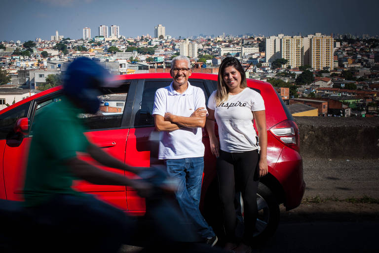 Alvimar da Silva e a filha, Aline, sua sócia, em frente a um carro vermelho, com vista para o bairro da Brasilândia