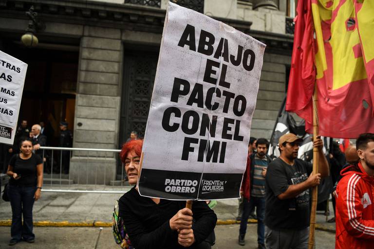 Pessoas seguram cartazes em protesto em Buenos Aires contra negociação do governo