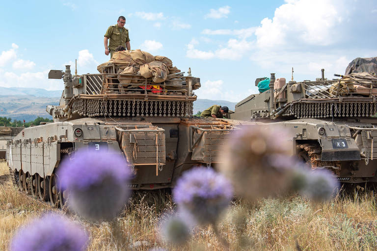 Soldado aparece em cima de tanque israelense; à esquerda, outro veículo blindado aparece pela metade; flores rochas aparecem esmaecidas à frente da imagem