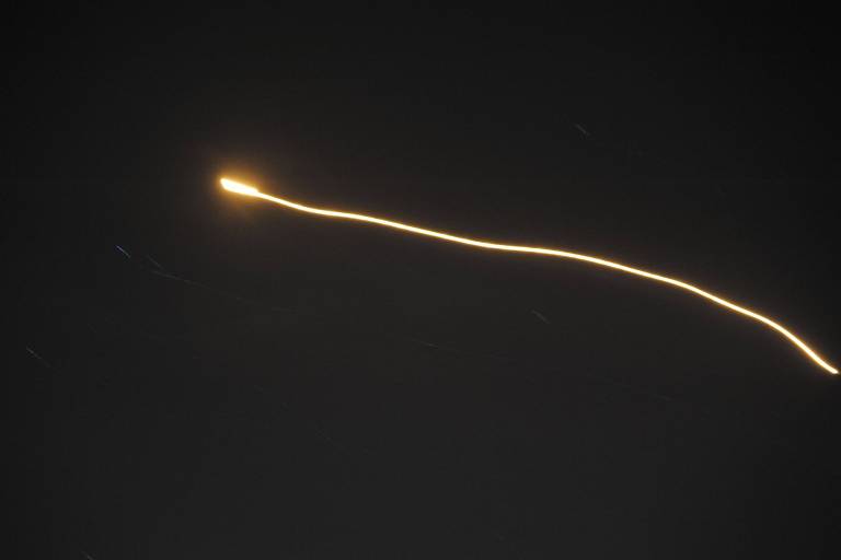 Míssil antiaéreo aparece com rastro de cor amarela em um fundo escuro, de céu claro noturno