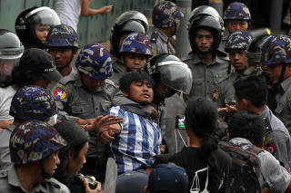 Myanmar police officers detain a student who takes part in a rally demanding peace at the war-torn Kachin State, in Yangon