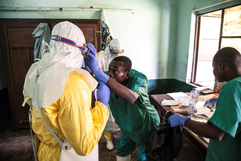Enfermeiros e médicos vestem equipamento de proteção para atender pacientes com suspeita de ebola em hospital em Bikoro, epicentro da epidemia, na República Democrática do Congo. 
