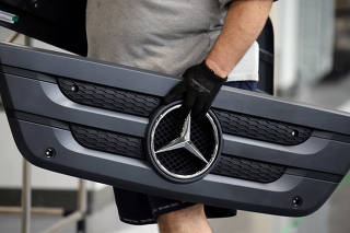 An employee carries a component of a truck at Mercedes Benz's trucks and buses manufacturing plant in Sao Bernardo do Campo