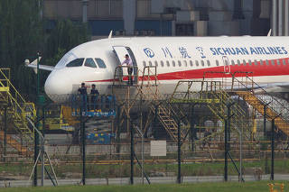 Workers inspect a Sichuan Airlines aircraft that made an emergency landing after a windshield on the cockpit broke off, at an airport in Chengdu