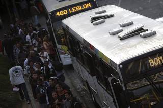 People wait in line to get into a bus during a 48-hour bus strike in Rio de Janeiro