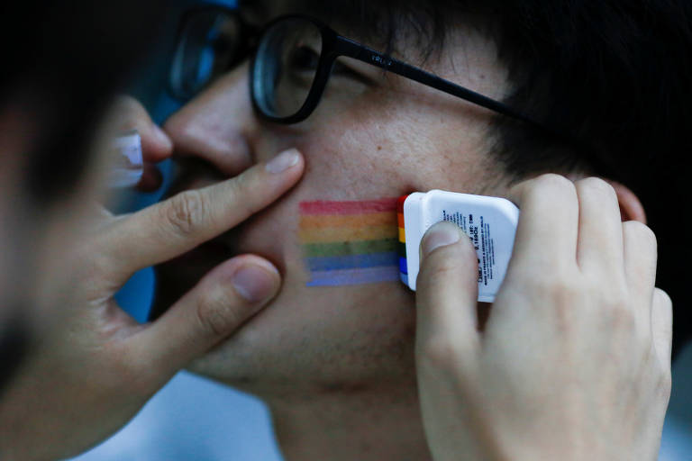 Manifestante pinta o rosto com o símbolo do arco-íris antes de evento contra a homofobia em Pequim 