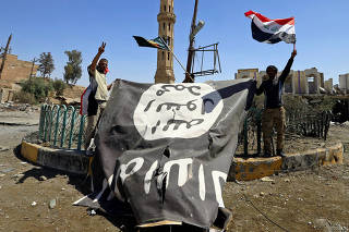 Shi'ite Popular Mobilization Forces (PMF) members hold an Islamic State flag, which they pulled down, during the war between Iraqi army and Shi'ite Popular Mobilization Forces (PMF) against the Islamic State militants in Tal Afar