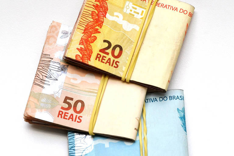 Foto de três maços de dinheiro de R$20, R$50 e R$100 reais. 