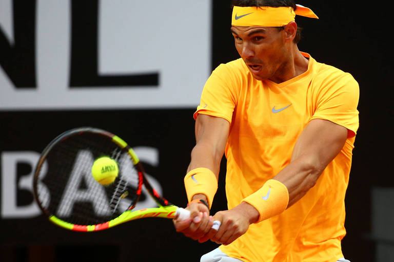 Tenista Rafael Nadal rebate a bola segurando a raquete com as duas mãos