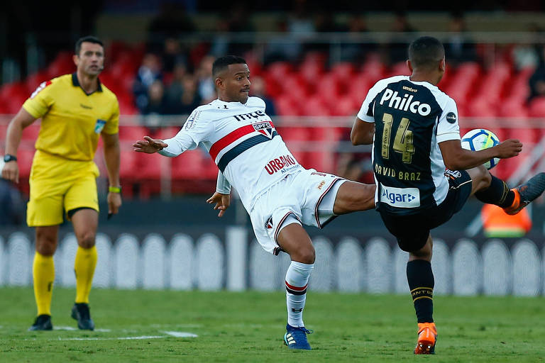 Um jogador do São Paulo chuta a bola enquanto o santista David Braz também tenta atingi-la