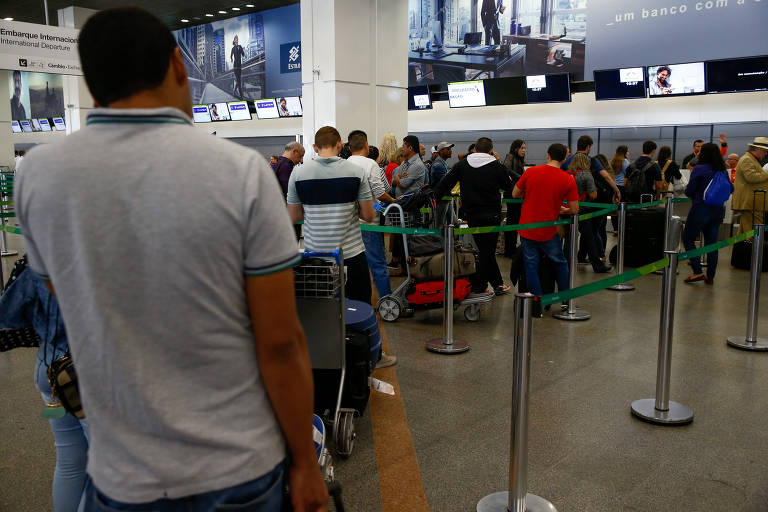 Passageiros esperam em fila para reacomodação, após terem seu voo cancelado devido ao desabastecimento de combustível de aviação no aeroporto de Brasília