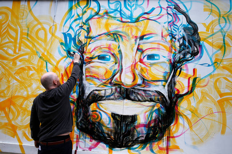 O artista Guy McKinley pinta um mural com o rosto de Mohamed Salah, na cidade de Liverpool