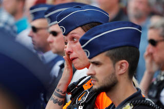 A policewoman reacts during a minute of silence in Liege