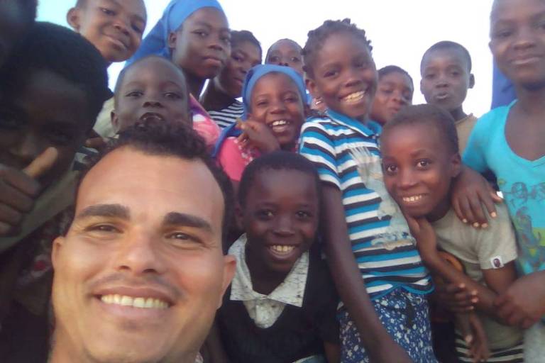 Eduardo Henrique de Moura cercado de crianças durante viagem a Moçambique, na África 