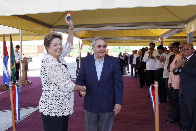 Dilma Roussef cumprimenta raul castro em cerimônia; ambos sorriem