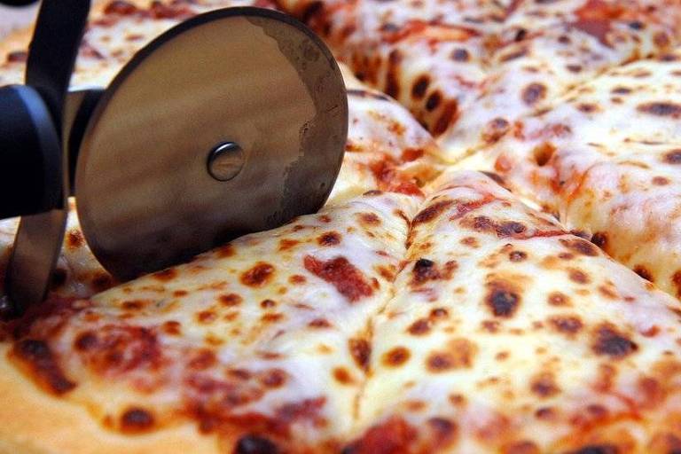 Pizza de mussarela sendo fatiada