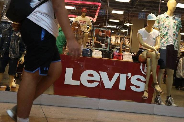 pedestre passa em frente a loja com letreiro "levi's"