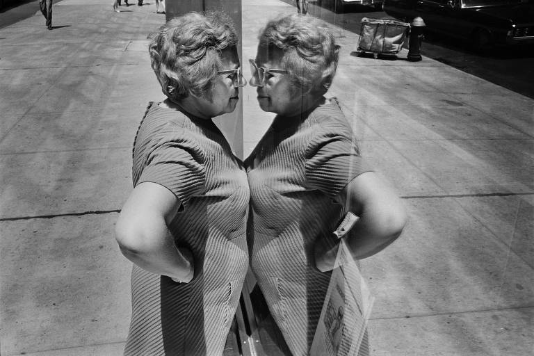 Mulher se olha em vitrine de loja em Nova York, nos anos 1960