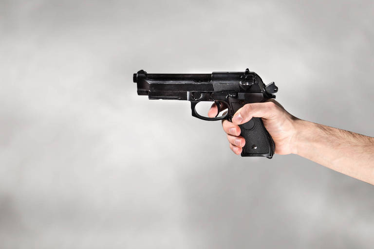 Mão segura uma pistola em fundo cinza