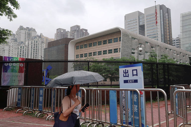 Mulher com guarda-chuva passa em frente ao consulado dos EUA em Cantão, na China