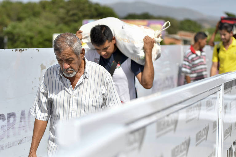 Homem carregando saco de farinha e idoso cruzam a fronteira de San Antonio, na Venezuela, para Cúcuta, na Colômbia  

