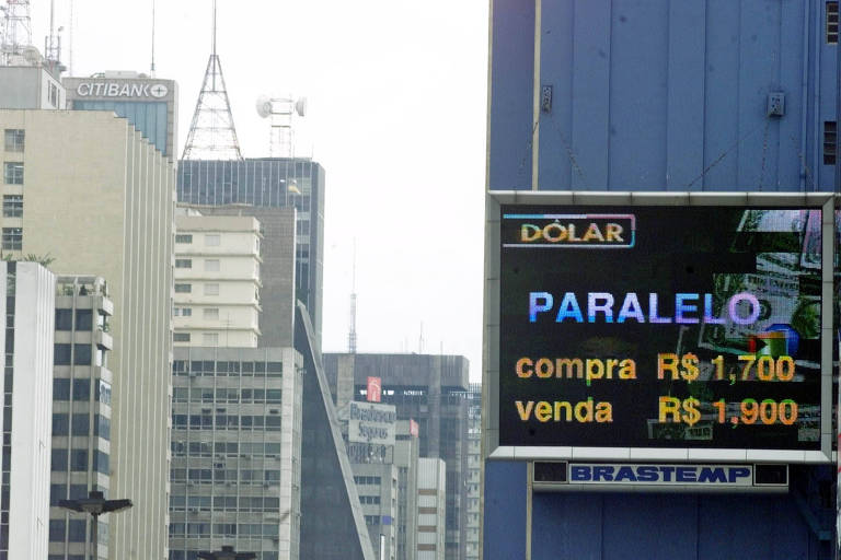 Painel com cotação do dólar; prédios da avenida paulista ao fundo