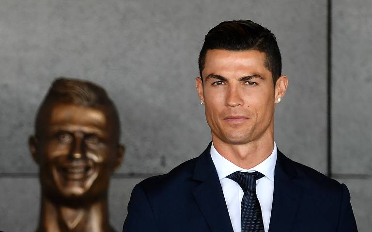 O jogador português posa para foto ao lado de busto feito em sua homenagem, no aeroporto de Funchal, na Ilha da Madeira, que ganhou seu nome. Cristiano Ronaldo nasceu na ilha