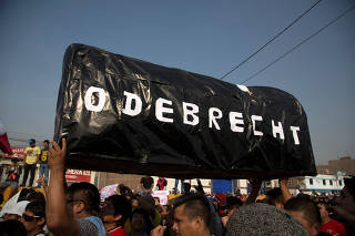 Protesters carry a mock coffin reads: 'Odebrecht' during a march against new road fees imposed for a highway built by Odebrecht-founded road consortium Rutas de Lima, in Lima,