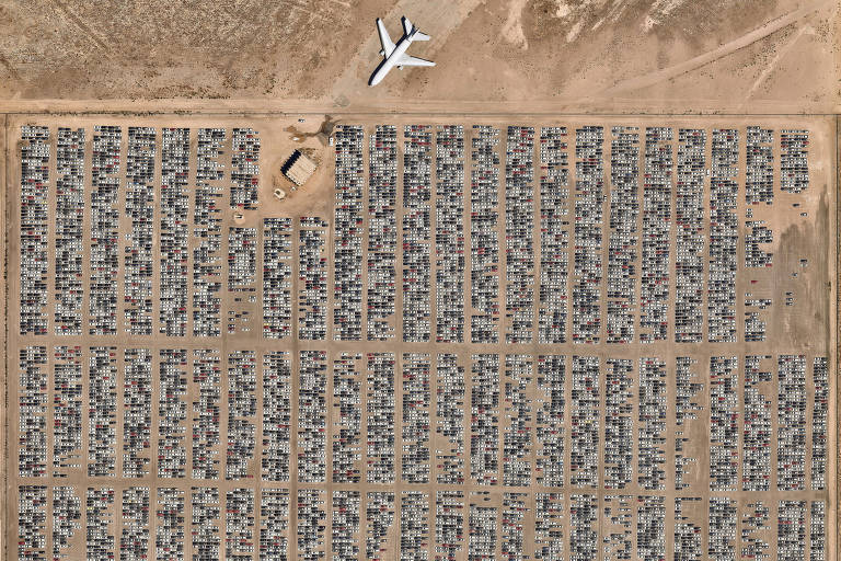vista áerea de deserto com milhares de carros estacionados e um avião, também estacionado