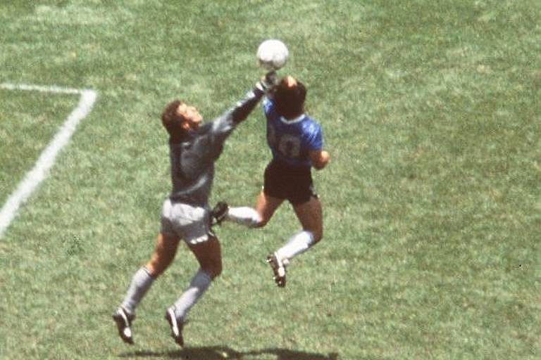 Maradona sobe para desviar a bola com a mão e marcar contra os ingleses