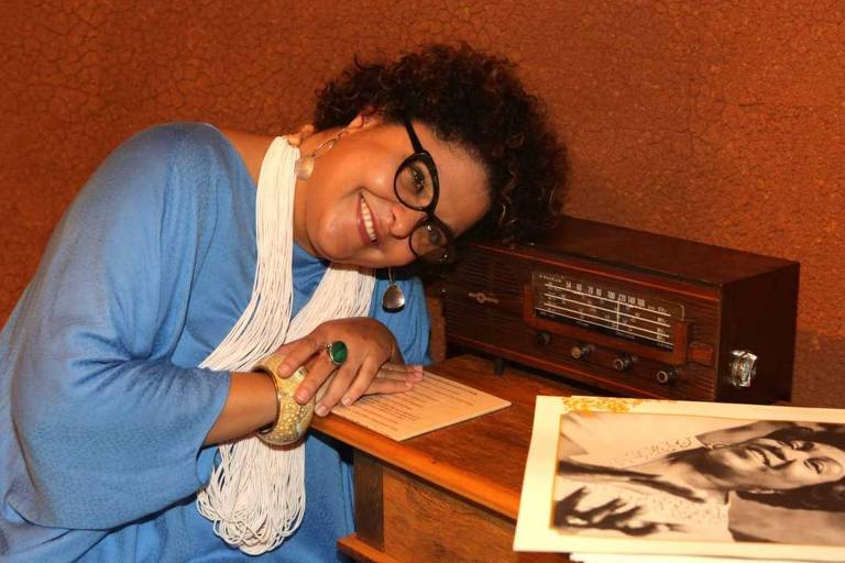 Fabiana Cozza se apoia em móvel em que estão um rádio antigo e um disco de Ivone Lara