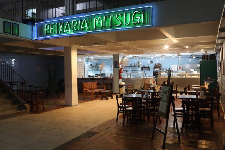 Entrada da Peixaria Mitsugi, com mesas e luminoso verde