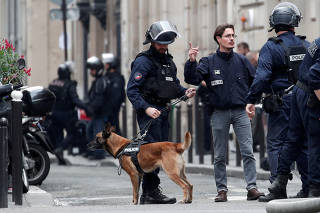 French police with their dog secure the street as a man has taken people hostage at a business in Paris