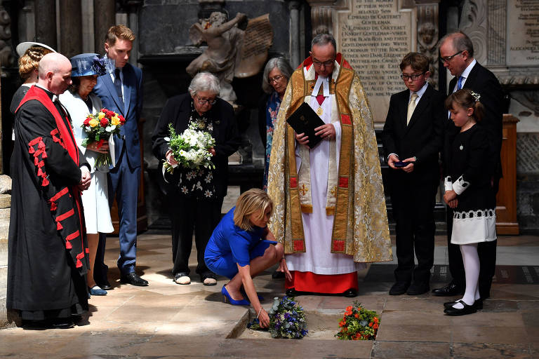 John Hall, dirigente de Westminster, acompanhado de Jane Hawking, primeira esposa de Stephen Hawking, observa Lucy Hawking, filha do cientista, homenagear o pai com flores no local de sepultamento de suas cinzas
